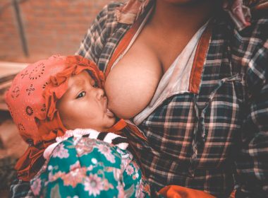 Ethnic young mother breastfeeding baby in village