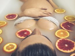 woman in white ceramic bathtub with sliced orange fruits