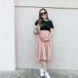 woman in black t-shirt and pink skirt standing beside wall