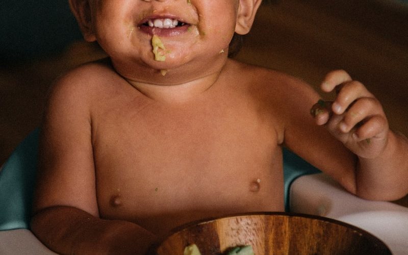 toddler eating vegetable in bowl