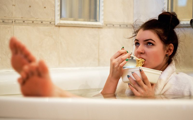girl in bathtub holding white ceramic mug