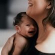 woman carrying smiling baby