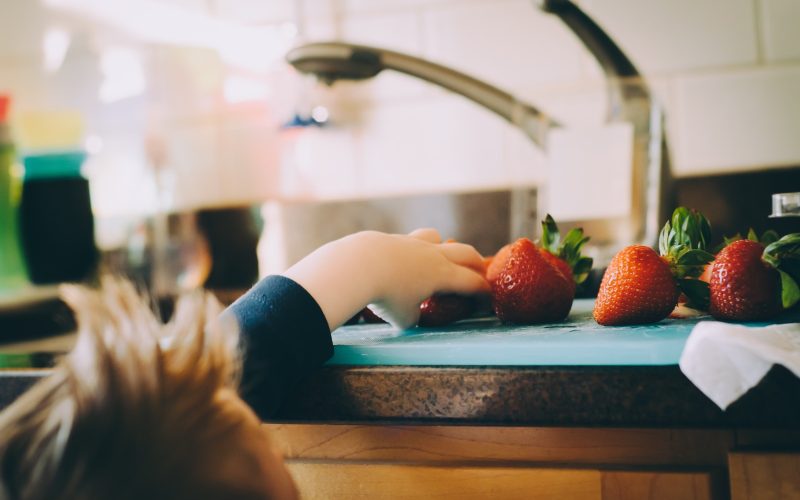 child picking strawberries in kitchen