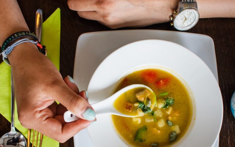 person holding spoon with soup on it