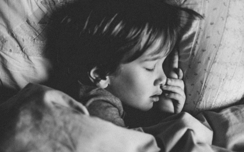 grayscale photo of girl sleeping on white pillow